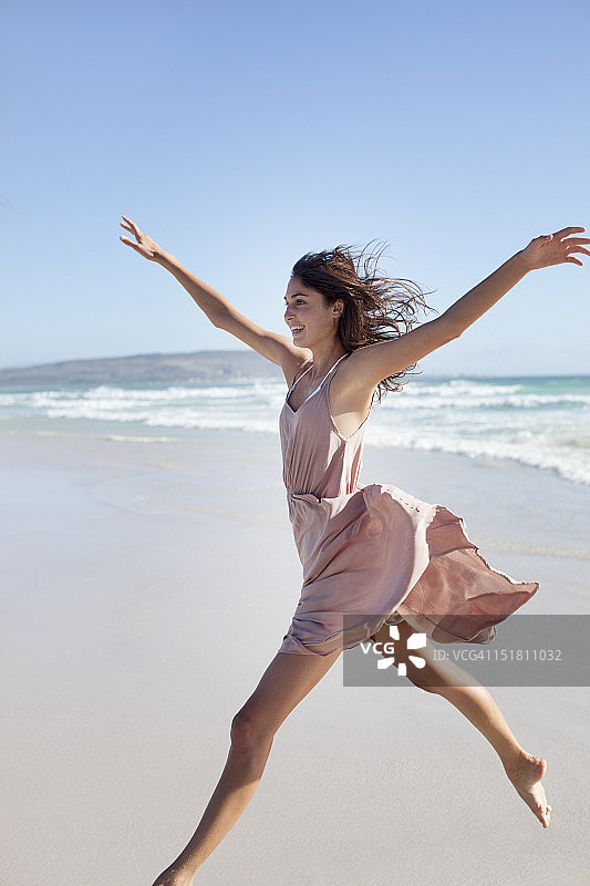 在海滩上张开双臂奔跑的精力充沛的女人图片素材