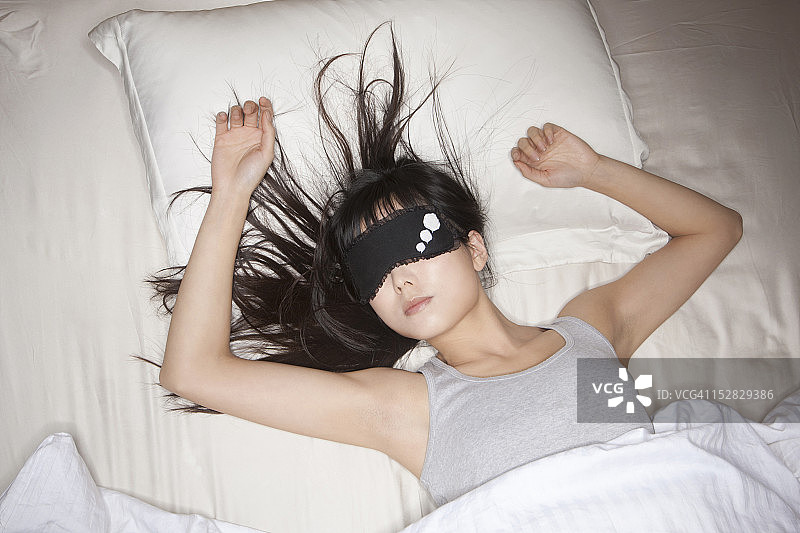 女人戴着面具在床上睡觉图片素材
