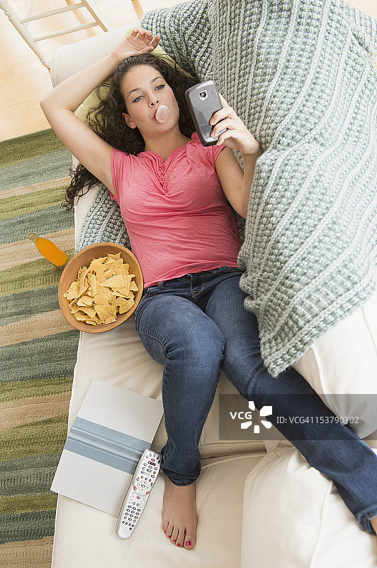 少女在沙发上吃垃圾食品发短信图片素材