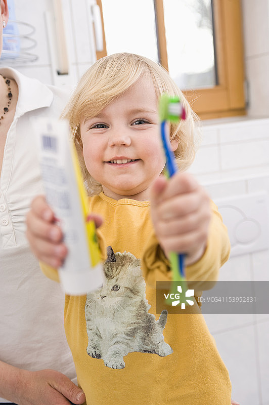 女孩展示牙刷和牙膏，微笑着图片素材