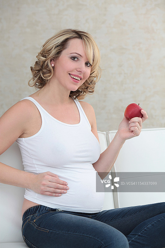 坐在沙发上拿着苹果的孕妇图片素材