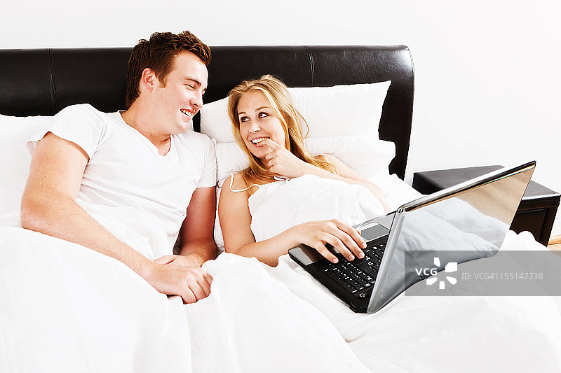 一对夫妇在床上用笔记本电脑图片素材