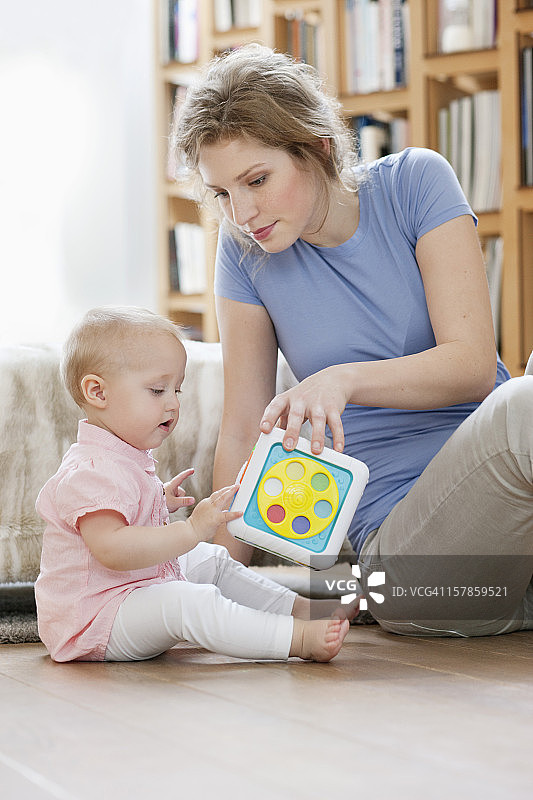 坐在女儿旁边的一位妇女在玩玩具图片素材