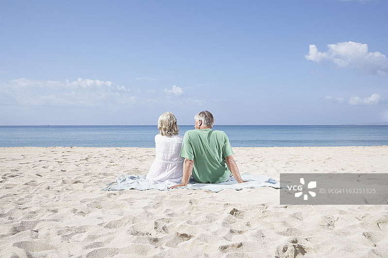 西班牙，马略卡岛，坐在海滩上的老夫妇图片素材