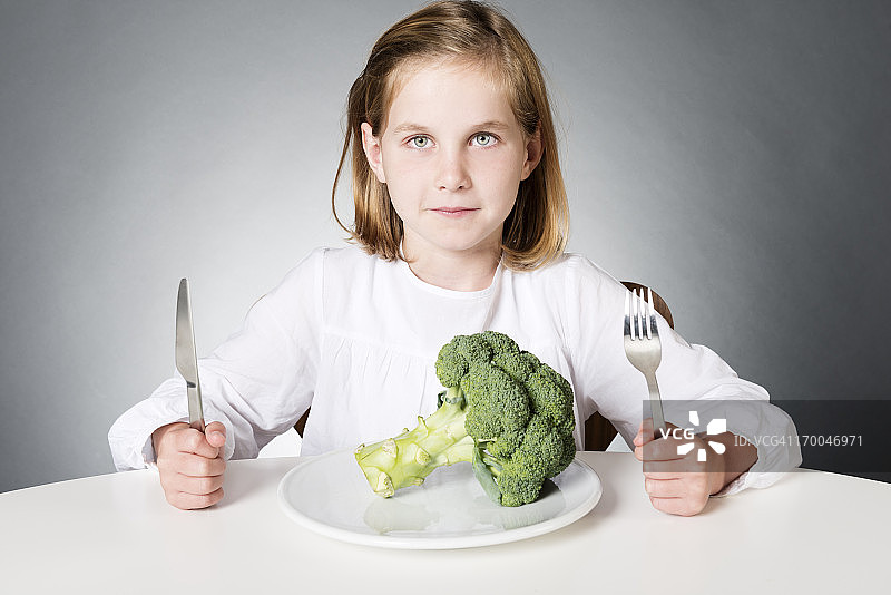 7岁的小女孩在吃花椰菜图片素材