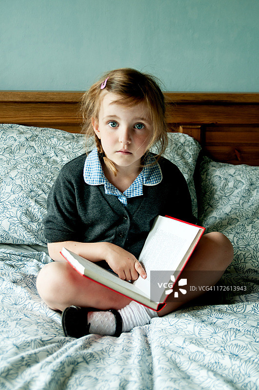 小女孩坐在床上看书图片素材