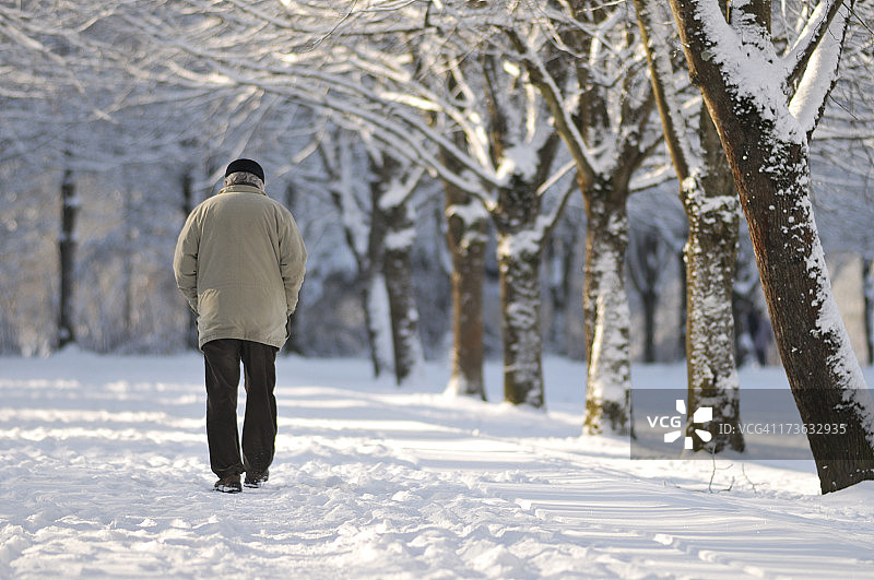 老人在白雪覆盖的公园里散步图片素材