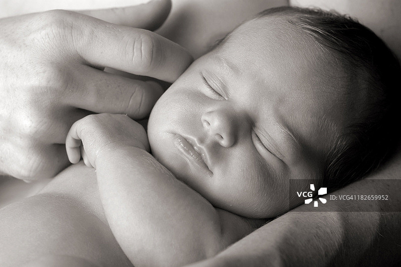 新生儿在父亲慈爱的怀抱中的黑白图像图片素材