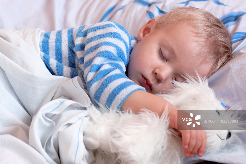 可爱的小男孩和玩具一起睡觉图片素材