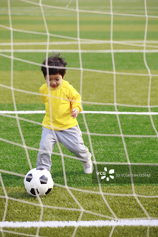 小女孩在草坪上踢足球图片素材