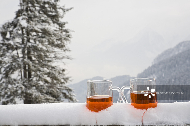 两杯饮料坐在一个被雪覆盖的窗台上图片素材