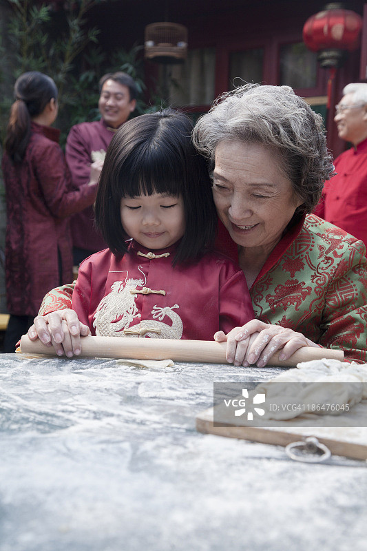 奶奶和孙女穿着传统服装包饺子图片素材