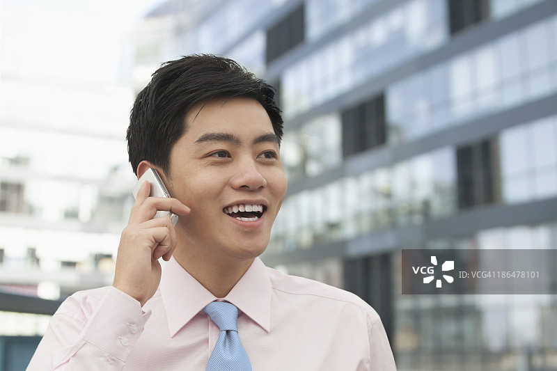 身穿粉色衬衫的年轻商人在电话里，中国北京图片素材