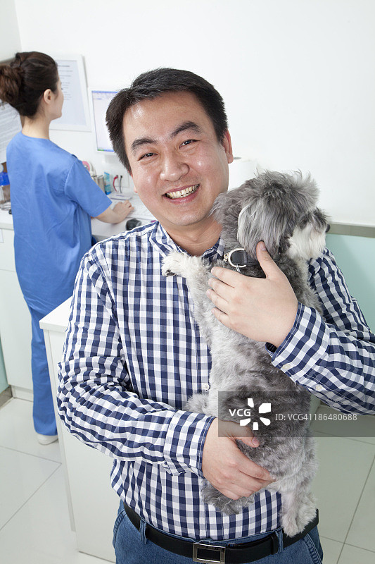 男人和宠物狗在兽医的办公室图片素材