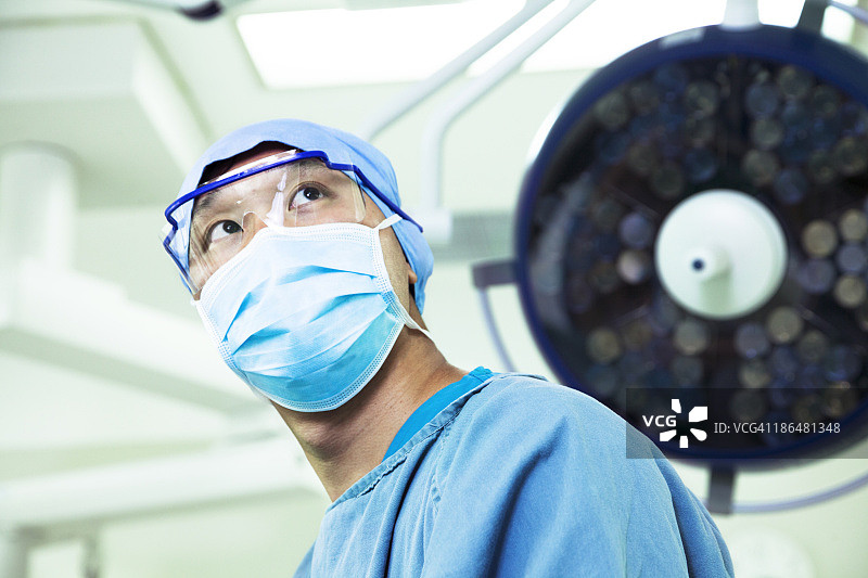 低角度的外科医生戴着手术口罩和眼镜在手术室图片素材