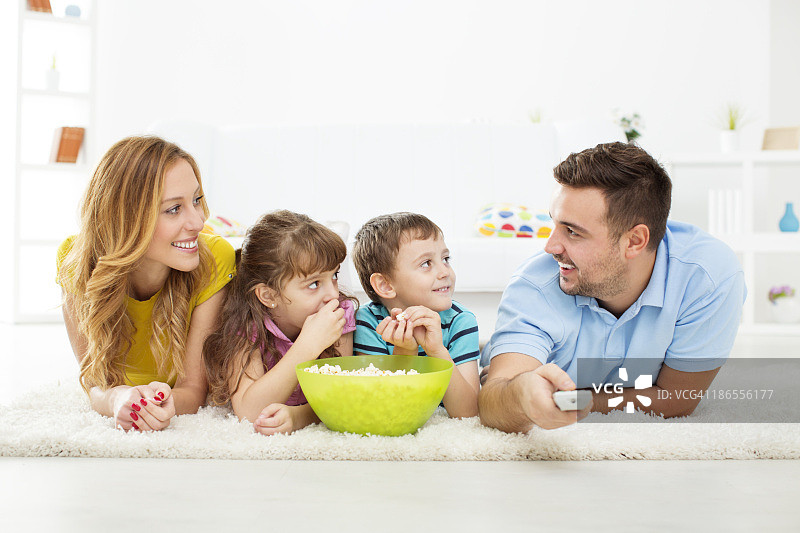 快乐的家庭吃爆米花和看电视。图片素材
