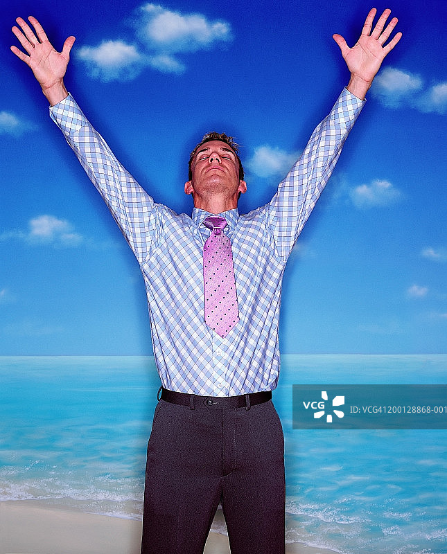 商人在热带海滩上伸懒腰，举起手臂，闭上眼睛图片素材