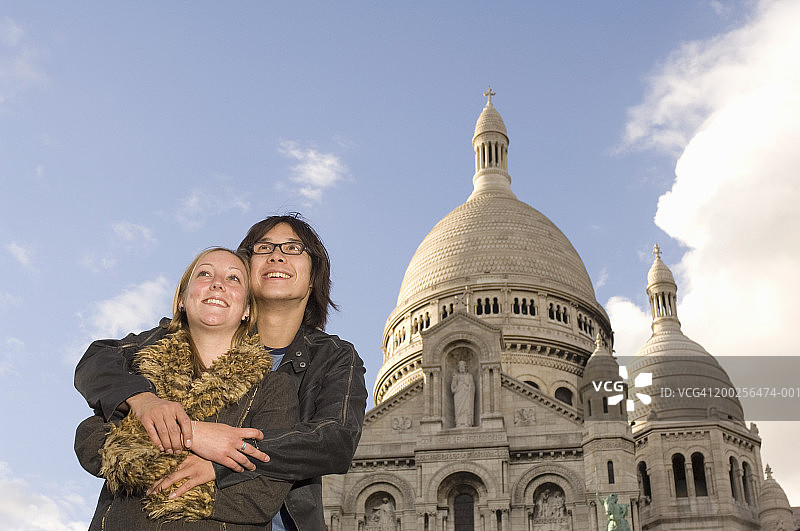 法国，巴黎，一对年轻夫妇在圣心教堂旁拥抱，微笑着图片素材