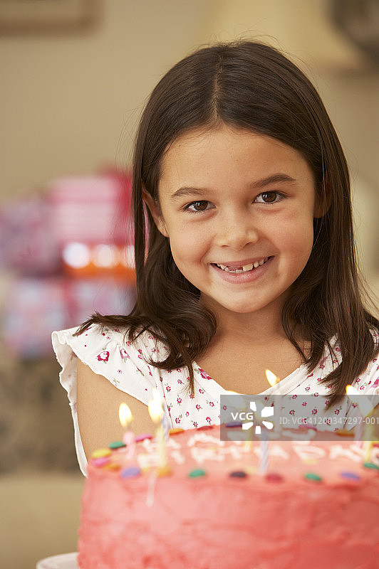 女孩(5-7)拿着生日蛋糕，微笑着，肖像，特写图片素材