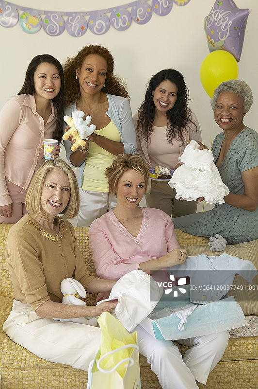 一群妇女聚集在迎婴派对的沙发旁，微笑着，画像图片素材