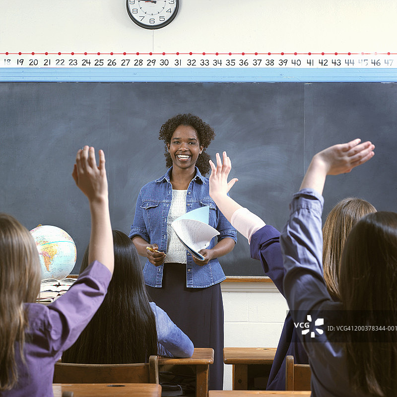 女同学(9-11)在课堂上举手，老师微笑图片素材