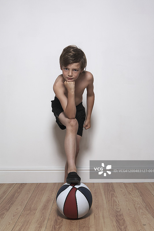 男孩(8-10)脚踩篮球，室内，人像图片素材