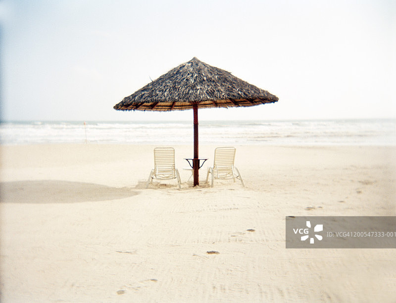 沙滩上的躺椅和竹茅草伞图片素材