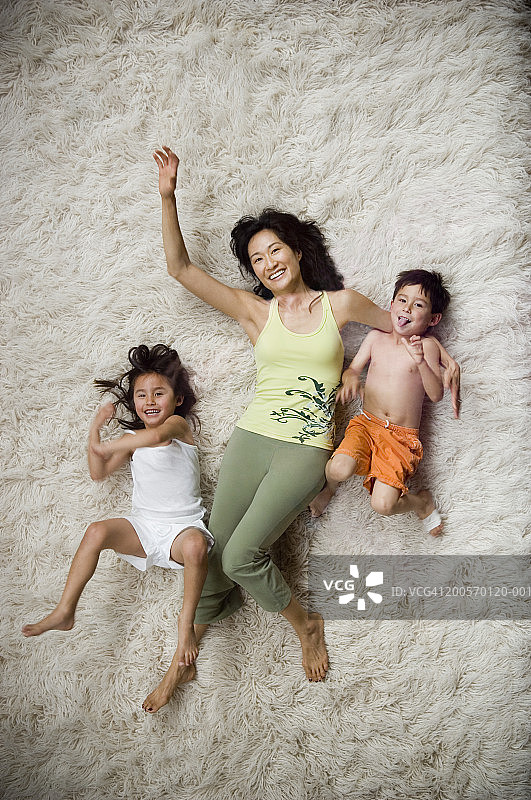 母亲和孩子(4-7)放松在毛茸茸的地毯上，俯视图片素材