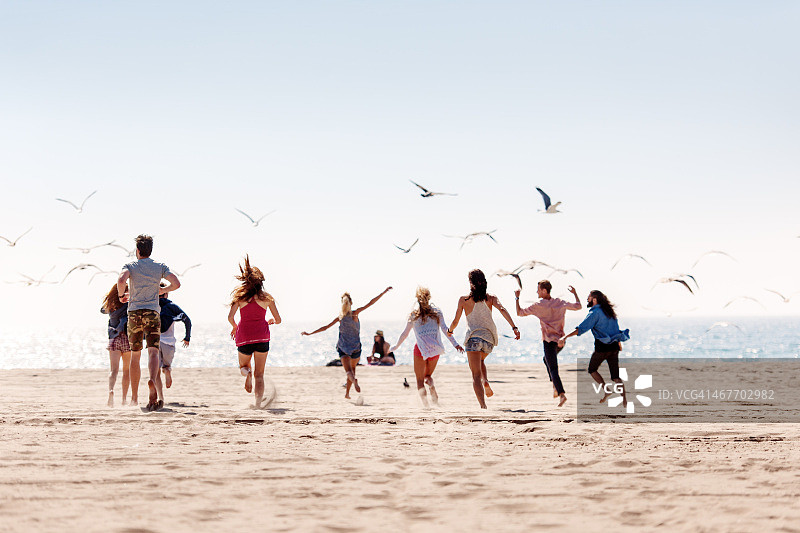 一群朋友在海滩上跑步图片素材