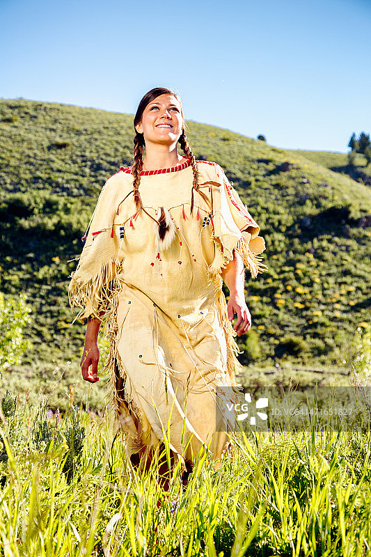 快乐的英雄印第安土著少女行走在草地上图片素材