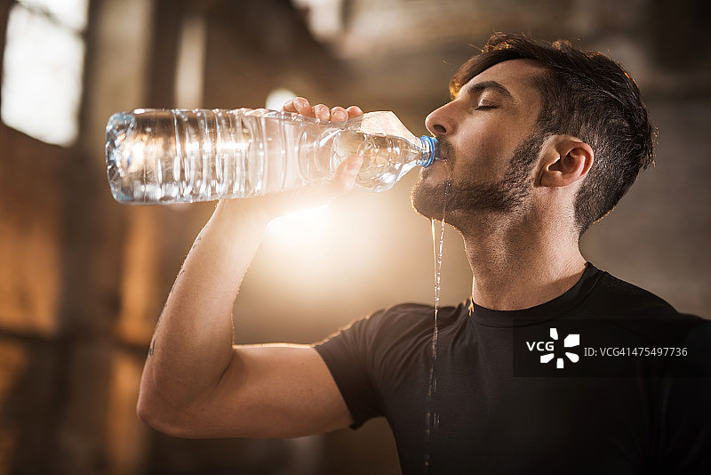 年轻口渴的运动员在运动后喝水。图片素材