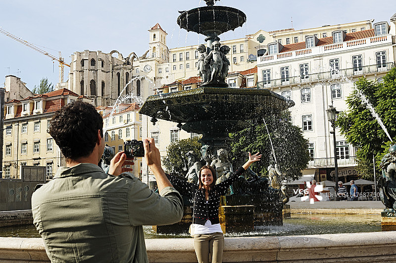 葡萄牙，里斯本，拜沙，罗西奥，佩德罗广场四世，一对年轻夫妇在喷泉前拍照图片素材