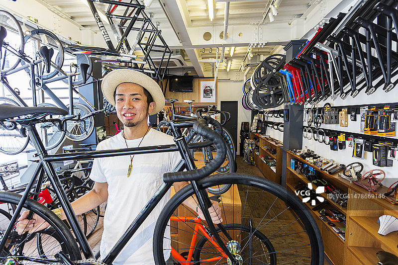 日本小商人在他的自行车店里拿着一辆自行车图片素材