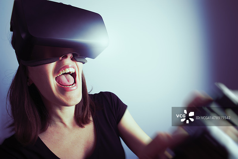 女人用虚拟现实耳机玩电子游戏图片素材