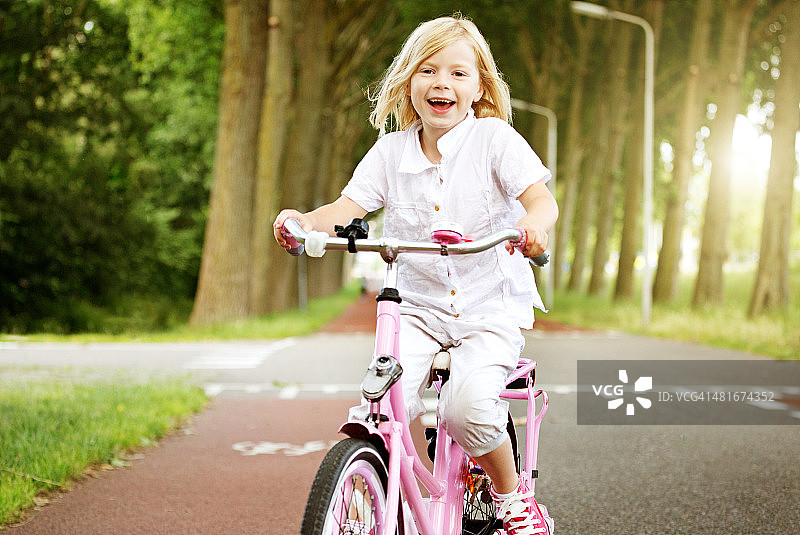 年轻的金发女孩骑着自行车图片素材