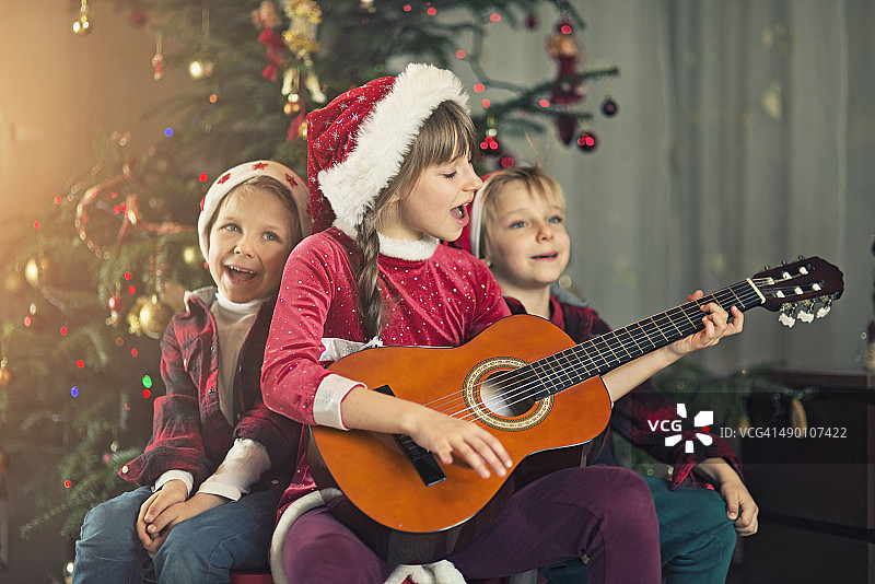 孩子们在圣诞树旁唱圣诞颂歌图片素材