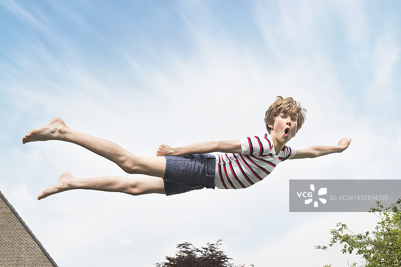孩子像超人一样在空中飞翔图片素材