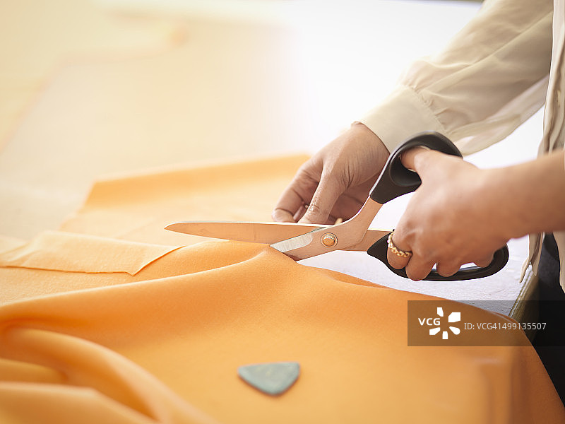 服装设计师在服装设计工作室裁剪布料，特写图片素材
