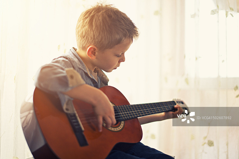 小男孩在练习吉他。图片素材