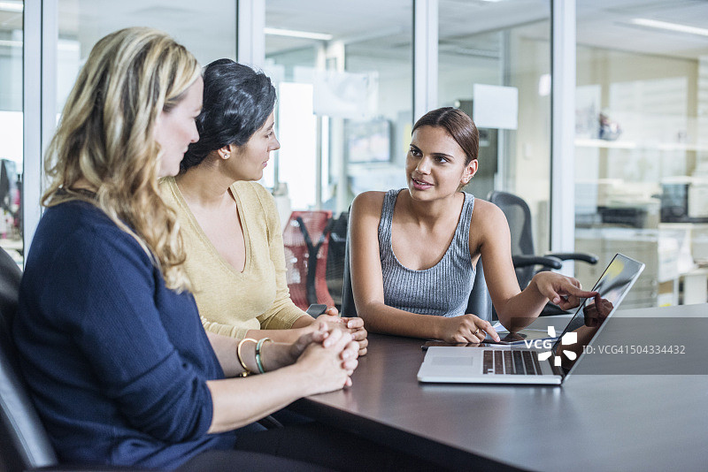 三个不同种族的女人在现代办公室里使用笔记本电脑图片素材