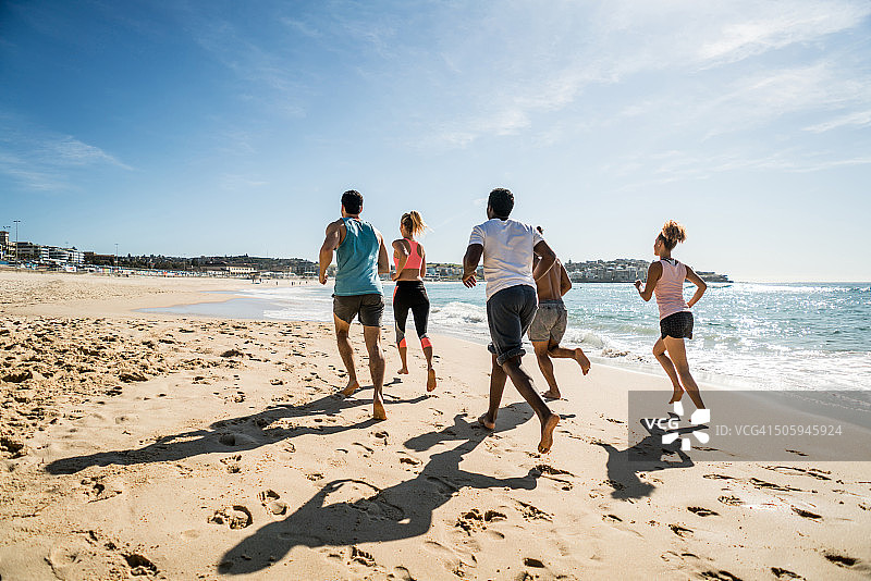 一群健康的人在海滩上跑步图片素材
