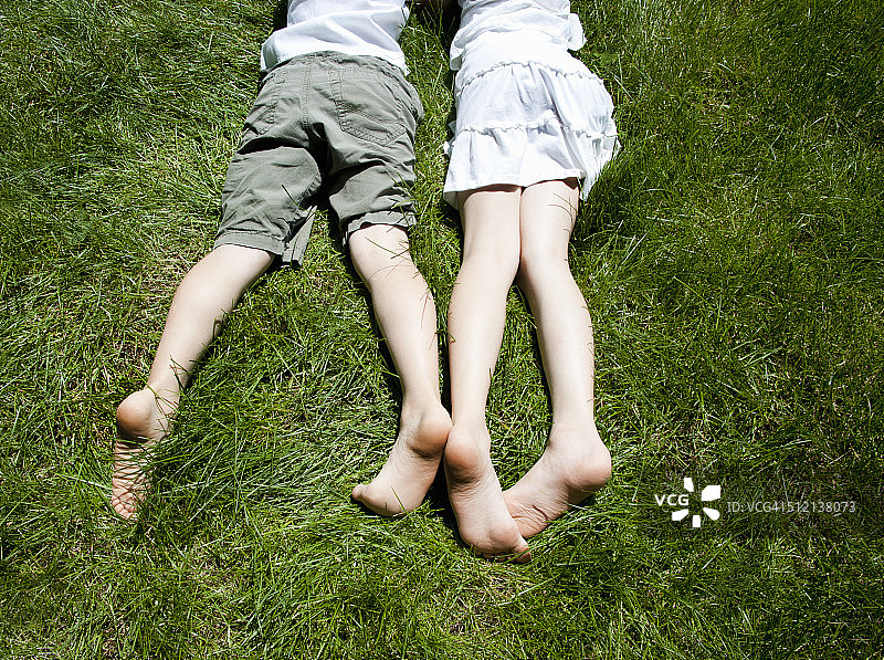 俯瞰兄弟姐妹们躺在草地上的腿图片素材