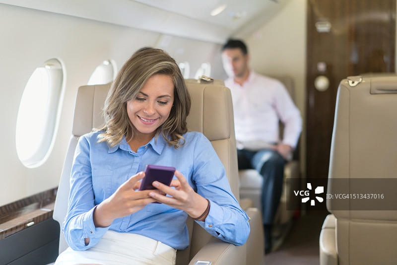 商务女性坐飞机旅行，发短信图片素材