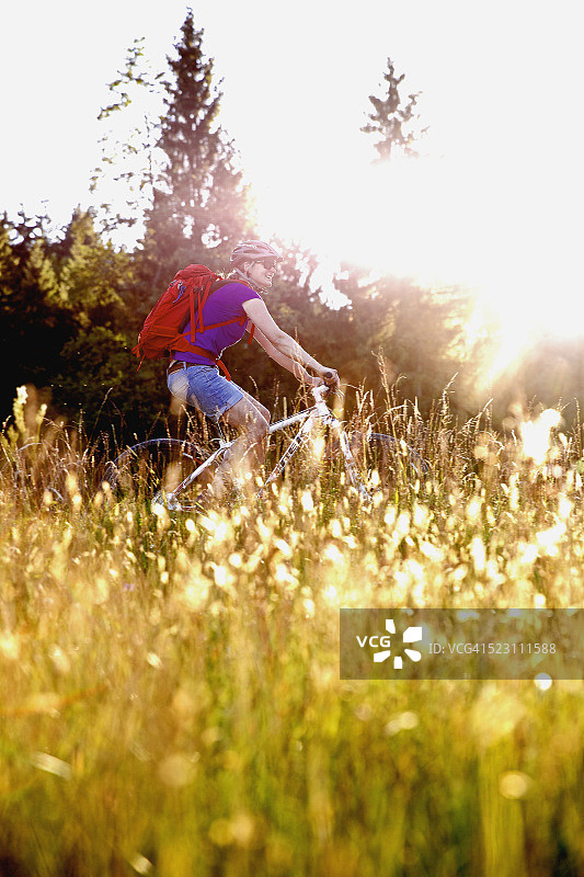 在草地上骑着自行车的女人图片素材