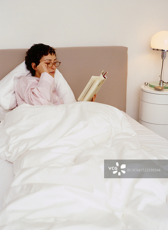 躺在床上看书的年轻女子图片素材