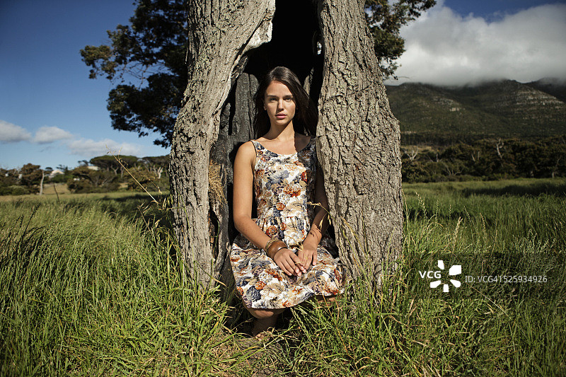 年轻女子的肖像蹲在空树干图片素材