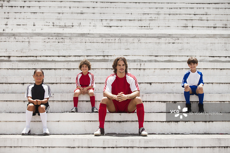 孩子和年轻人坐在空荡荡的足球场里图片素材