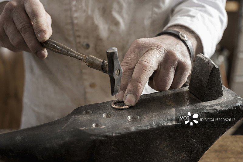 德国巴伐利亚，工匠在车间内对铜环进行成型图片素材