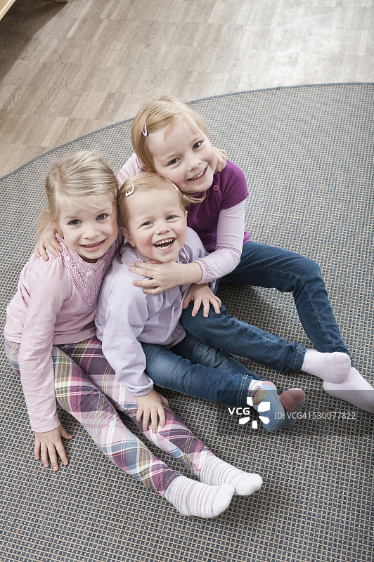 三个小女孩，最好的朋友，坐在幼儿园的地上，高高在上图片素材