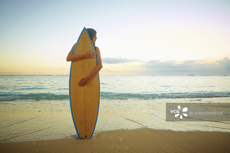 一个白人女孩在沙滩上拥抱冲浪板图片素材